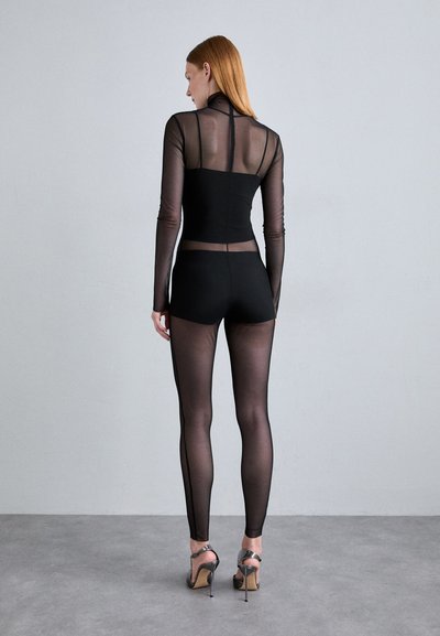 Black sheer long-sleeve top and leggings set with fitted design. Textured mesh and solid fabric combined, with subtle seams and accents.