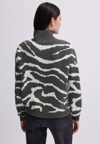 Groen en wit gestreept sweater met een hoge ribbelsboord, ruime pasvorm en zachte textuur. Heeft een gedurfde golvende patroon over de achterkant.