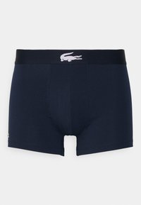 Marinblå boxershorts i mjukt tyg, med en kontrasterande svart midja och en vit krokodil-logotyp framtill.