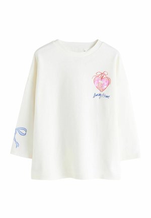 Hvid langærmet T-shirt med en farverig hjertegrafik med en sløjfe og teksten "Lucky Heart" på fronten samt en blå bånddetalje på ærmet.