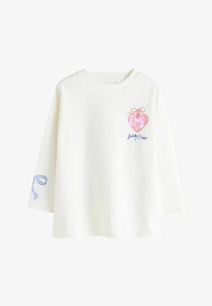 Baltas ilgomis rankovėmis marškinėlis su spalvingu širdies piešiniu su kaspinu ir užrašu „Lucky Heart“ priekyje bei mėlynos spalvos juostos detalė ant rankovės.