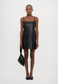 Rochie din piele neagră cu bretele subțiri, bust ajustat și lungime deasupra genunchilor. Textură netedă, design minimalist, asortată cu o geantă potrivită.