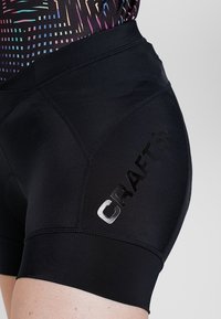 Black athletic shorts made of stretchy fabric, featuring a smooth texture and a shiny "CRAFT" logo on the side.
