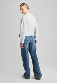 Light gray, fuzzy sweater paired with loose blue jeans. The sweater has a rounded neckline and ribbed cuffs; the jeans feature rear pockets.