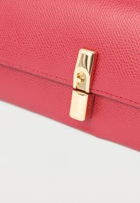 Geantă de mână roz din piele texturată, cu închizătoare aurie și detalii metalice accentuate, având cusături vizibile pe margini.