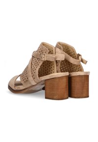 Sandalias de tacón de gamuza beige con diseño perforado, correa ajustable en el tobillo y tacón de madera apilado. Suela plana y estilo de punta abierta.