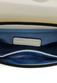 Bolso negro con un interior azul claro, que cuenta con una etiqueta blanca y costuras contrastantes a lo largo de los bordes. Incluye un bolsillo con cremallera.