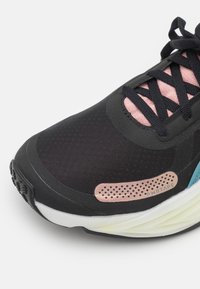 Černá sportovní bota s růžovými akcenty, texturovaný síťovaný svršek, šněrování a světle zelená mezipodešev s perforovaným detailem.