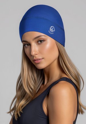 Bonnet de bain en tissu extensible bleu avec coutures minimales et détail logo, design ajusté, texture lisse, porté par une personne aux cheveux longs.