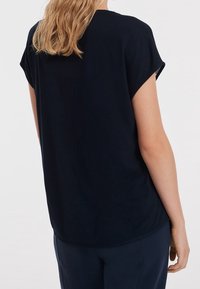 T-shirt navy blu a maniche corte con vestibilità rilassata, scollatura rotonda e texture morbida e liscia. Orlo leggermente curvato sul fondo.