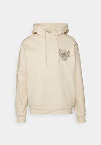 Sudadera con capucha color crema con cordón en la capucha, bolsillo delantero y un emblema gráfico con hojas de laurel. Tela suave y texturizada, puños acanalados.