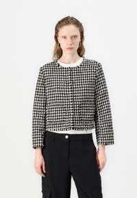 Jachetă croită cu model houndstooth alb-negru, cu mâneci lungi și guler rotund, având închidere cu nasturi și țesătură texturată.