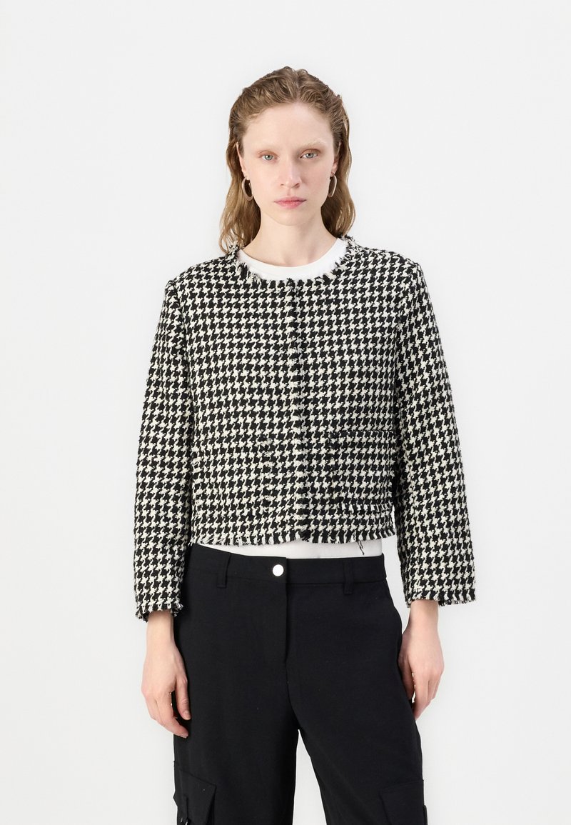 Jachetă croită cu model houndstooth alb-negru, cu mâneci lungi și guler rotund, având închidere cu nasturi și țesătură texturată.