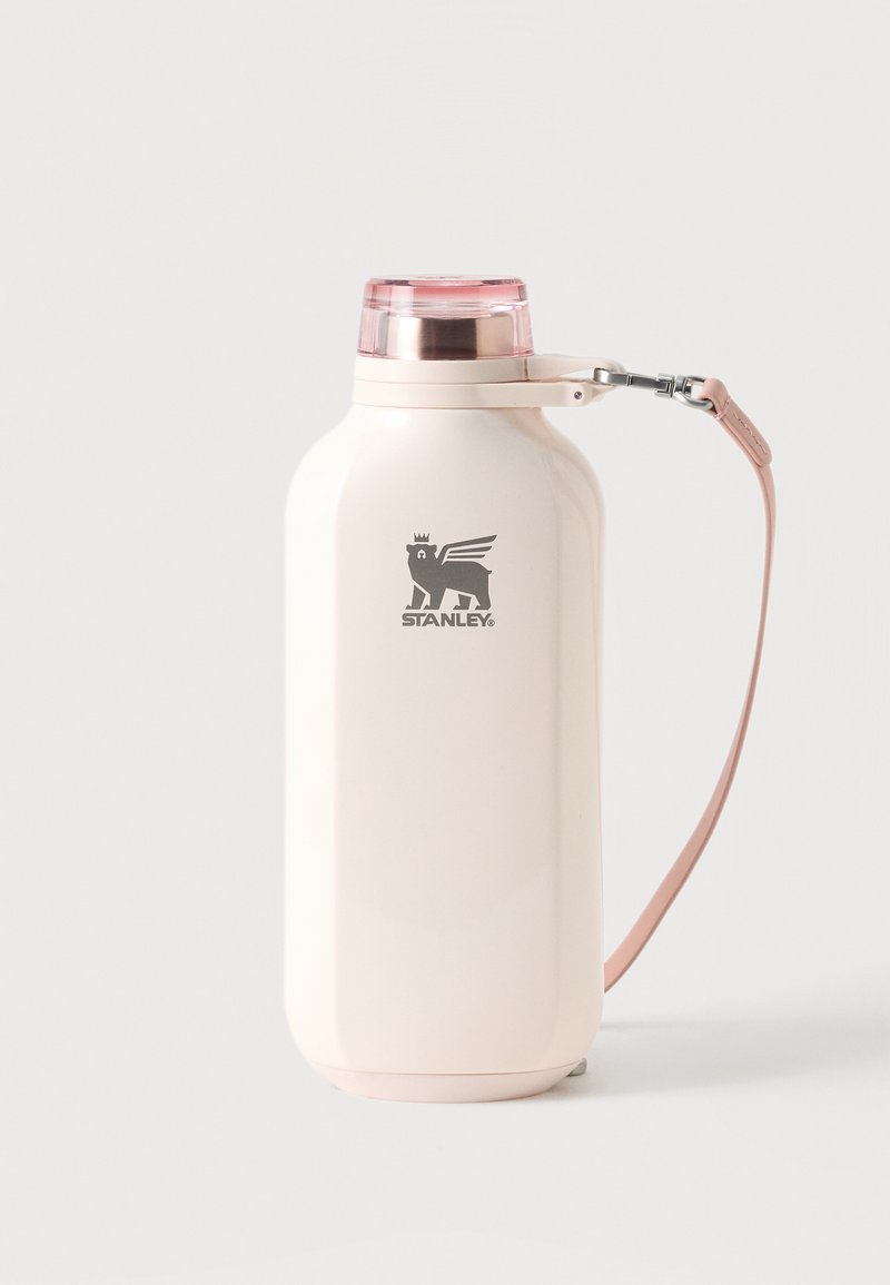 Μπουκάλι Stanley μονωμένο σε κρεμ χρώμα με ροζ καπάκι και αποσπώμενο ροζ λουράκι μεταφοράς σε λευκό φόντο.