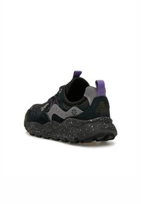 Sneaker con una parte superiore nera e grigia, caratterizzata da una finitura in suede testurizzato e una suola in gomma nera maculata, accentuata da un inserto sul tallone di colore viola.