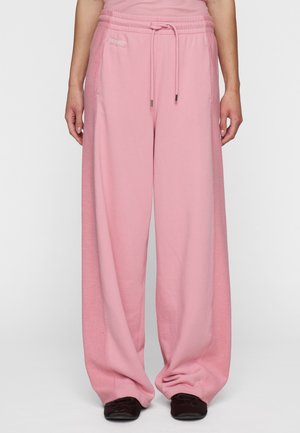 Pantalones de chándal anchos rosa con una superficie texturizada y cinturilla elástica. Incluye bolsillos laterales y un cordón para ajuste.