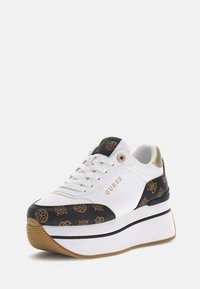 Sneaker platform bianca con accenti neri a motivo, logo dorato e tallone texturizzato. Caratterizzata da lacci piatti e una suola in gomma con design rigato.