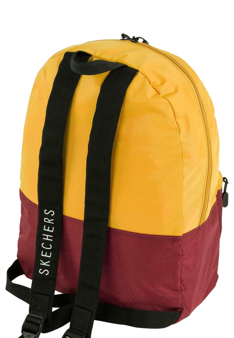 Mochila con parte superior amarilla y parte inferior marrón. Presenta correas ajustables negras y un cierre de cremallera. Logo "SKECHERS" en el lado.