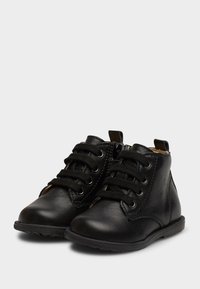 Botas de cuero negro hasta el tobillo con punta redondeada, cordones en la parte delantera, cierre de cremallera y suela de goma plana. Interior con forro suave para mayor comodidad.