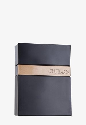 Sort rektangulær parfume flaske med et vandret metallisk gyldent bånd præget med "GUESS" tværs over den øvre midtersektion.