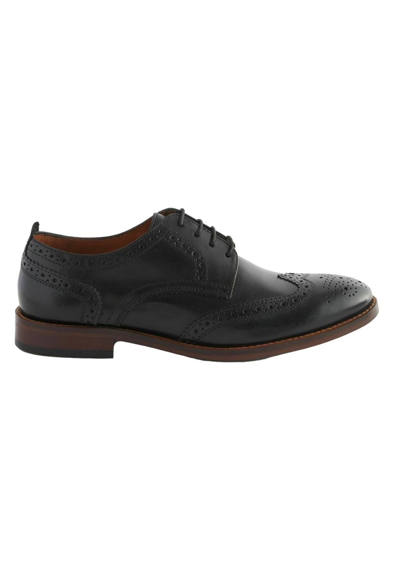 Black leather oxford shoe with perforated brogue detailing, rounded toe, and a brown stacked heel. Laces are threaded through five eyelets.