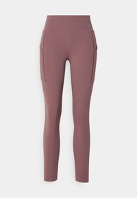 Leggings realizzati in tessuto elasticizzato di colore malva, con vita alta, tasche laterali e una texture liscia. Dettaglio di branding minimo sulla vita.