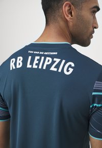 RB Leipzig sportmez sötétkékkel, fehér részletekkel. Kerek nyakkivágással, rövid ujjakkal rendelkezik, hátul pedig a "BÁRMIT MEG TUDSZ CSINÁLNI" felirat található.