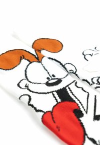 Calzini bianchi con un design di un cane cartone animato; orecchie arancioni, contorni neri e accenti rossi. Texture morbida con un motivo a maglia.