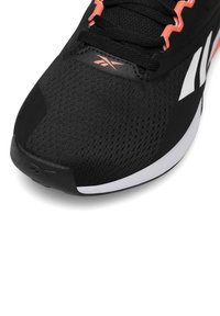 Must kasutatakse musta spordi kinga, millel on võrgust ülemine osa, tekstuuriga pind, valge põhi ning erksad oranžid aktsendid paeladel ja brändingul.