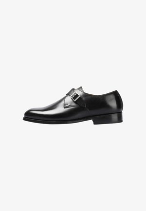 Zapato de vestir de cuero negro con punta redondeada, correa con hebilla única, textura suave y tacón bajo apilado, con detalles de costuras discretas.