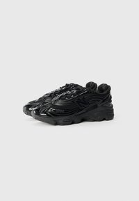 Black athletic shoes with a shiny, textured synthetic upper and padded tongue; features a thick, cushioned sole with contrasting accents.