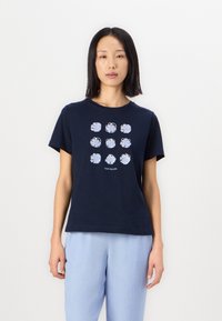 Marineblå bomull T-skjorte med et rutenett av ni lyseblå blomsterdesign. Rund hals og korte ermer. Løs passform.