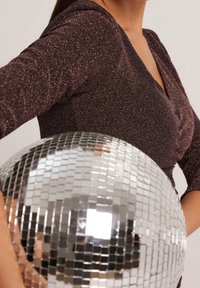 Lesklý tmavě fialový top s dlouhým rukávem a kulatým výstřihem, doplněný o reflexní disco kouli se čtvercovými zrcadlovými dlaždicemi.