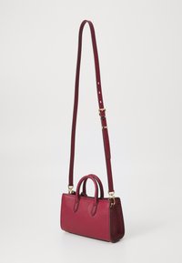Borsa a mano in pelle bordeaux con una forma strutturata, dotata di manici superiori e tracolla staccabile. Accenti in hardware color oro.