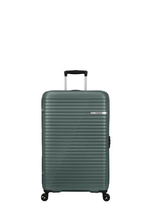 Hartschalenkoffer in Dunkelgrün mit linearer Rillenstruktur. Verfügt über einen ausziehbaren Griff und vier drehbare Rollen für einfache Mobilität.