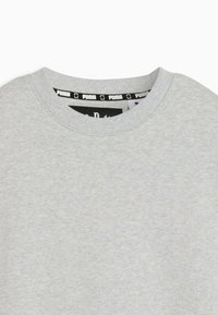 Gray sweatshirt with a ribbed crew neckline. Features a black and white Puma logo label inside the collar. Soft, textured fabric visible.
