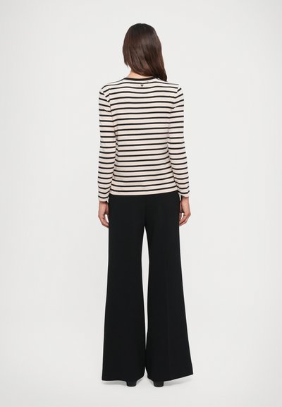 Striped long-sleeve top in cream and black, paired with wide-leg black pants. Smooth texture, fitted design, and round neckline.