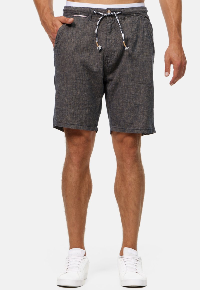 Donkergrijze denimachtige shorts met een elastische tailleband en trekkoord, uitgevoerd in een gestructureerde stof en zijzakken. Gecombineerd met witte sneakers.