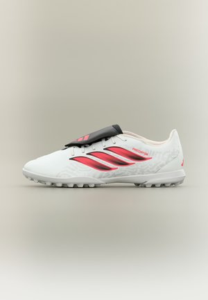Λευκό και κόκκινο παπούτσι ποδοσφαίρου Adidas Predator με μαύρο κάλυμμα κορδονιών και υφή σόλας για τεχνητό χλοοτάπητα.