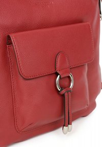 Borsa a mano rossa in pelle con finitura texturizzata, dotata di una tasca frontale con pattina, hardware di colore argento e un accento ad anello circolare.