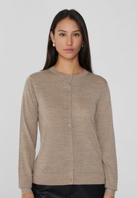 Beige gestrickte Freizeitjacke mit Rundhalsausschnitt und langen Ärmeln, die eine Knopfleiste und ein dezentes strukturiertes Muster aufweist.