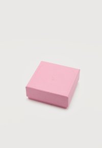Κλειστό μικρό τετράγωνο ροζ κουτί δώρου με διακριτικό ανάγλυφο λογότυπο στο καπάκι, τοποθετημένο σε απλό λευκό φόντο.