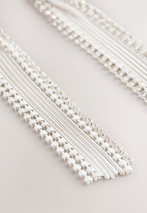 Weißer Stoffbesatz mit abwechselnden Strängen aus glatten Texturen und Perlendetails, durchgehend mit metallischen quadratischen und runden Akzenten.