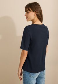 T-shirt bleu marine à manches courtes avec un col rond, en matériau côtelé, présentant une coupe décontractée et des accents de couture visibles.
