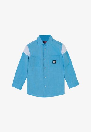 Camicia azzurro chiaro con bottoni, maniche lunghe, due tasche frontali, un motivo bianco a contrasto sulle spalle e una toppa con logo nero sul petto.