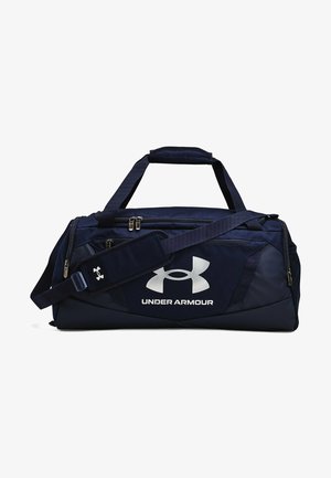 Navy duffel bag with a textured fabric, silver logo on the front, dual handles, and an adjustable shoulder strap with a cushioned pad.