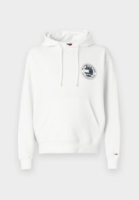 Balta džemperis su gobtuvu, pagamintas iš medvilnės mišinio, su priekinėmis kišenėmis, raišteliais ir suapvalintu grafiniu logotipu ant krūtinės. Raibos rankogaliai.