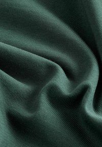Texturiertes dunkelgrünes Gewebe mit glatter Oberfläche und subtilen Rippungen, die sanfte Wellen und Falten im Material zeigen.