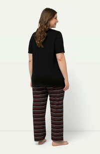 Top nero a maniche corte abbinato a pantaloni da lounge a righe orizzontali multicolori. Tessuto morbido con una vestibilità rilassata e senza loghi o decorazioni visibili.