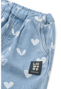 Ανοιχτό μπλε τζιν σορτς με λευκά σχέδια καρ διές, με ελαστική ζώνη μέσης και μια μαύρη ετικέτα μάρκας ραμμένη στη πλευρά.